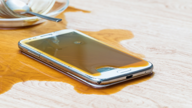 Smartphone with coffee spilled on wooden floor