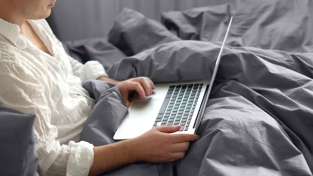 Person using MacBook on bed